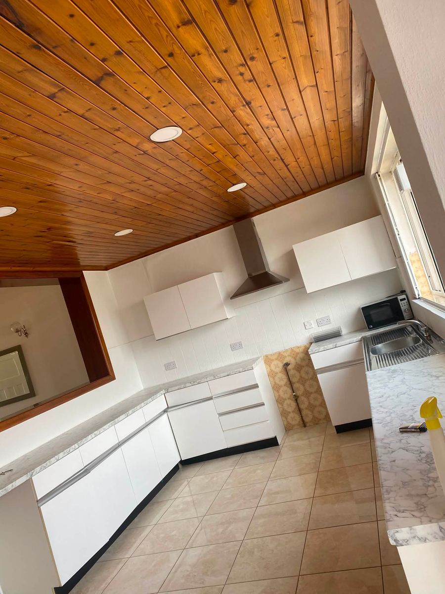 Finished kitchen with white units and a tiled floor